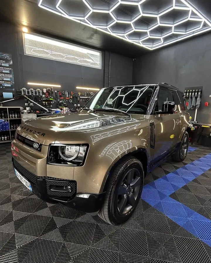 Land Rover Defender sous l'éclairage hexagonal de l'atelier après nettoyage complet