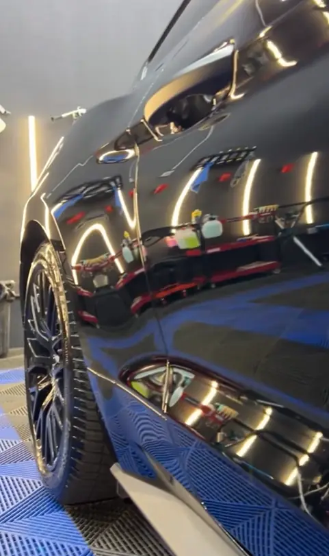 Reflets sur l'aile d'une Ford Mustang noire après polissage de la peinture
